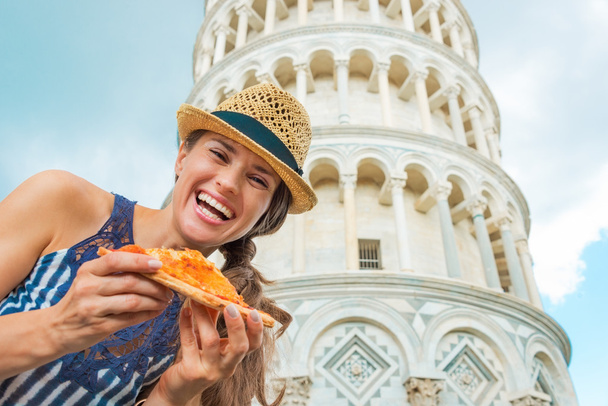 Portrait of happy young woman with pizza in front of leaning tow - Foto, imagen