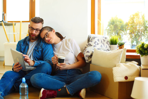 Happy couple planning decoration when moving home sitting on the floor. - Foto, Imagen