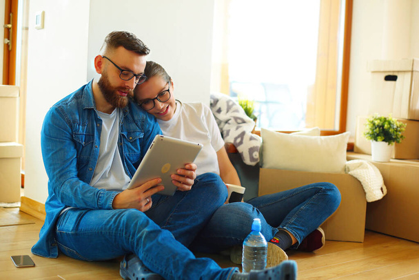 Happy couple planning decoration when moving home sitting on the floor. - Foto, Imagem