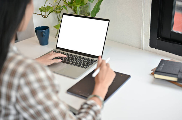 Крупный план азиатки, использующей ноутбук, работающей над своей работой в офисе. белый макет ноутбука - Фото, изображение