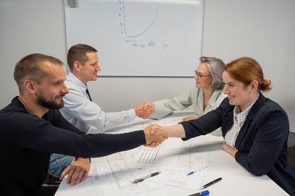 Business partners shake hands. Four business people are negotiating in the conference room - Fotoğraf, Görsel