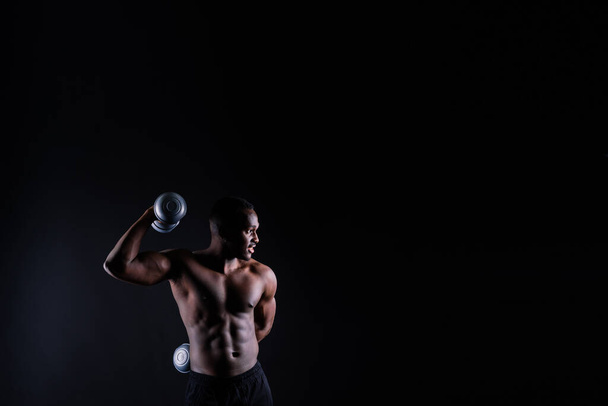 Portrait of happy african man with dumbbells over red and black background - Foto, Imagem