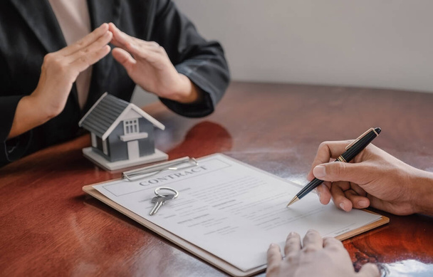 Υπογραφή σύμβασης με το χέρι αφού ο μεσίτης εξηγεί το επιχειρηματικό συμβόλαιο, το ενοίκιο, την αγορά, την υποθήκη, ένα δάνειο, ή ασφάλιση στο σπίτι στον αγοραστή. - Φωτογραφία, εικόνα