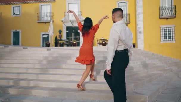Vášnivý hispánský pár tančící horkou choreografii na schodech. Sexy brunetka v červených šatech svůdně flirtuje s elegantním partnerem zpomaleným pohybem. Energičtí tanečníci předvádějící latinský styl. - Záběry, video