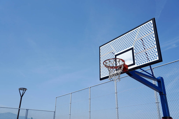 Mavi gökyüzünde boş bir sahada basketbol potası..                                 - Fotoğraf, Görsel