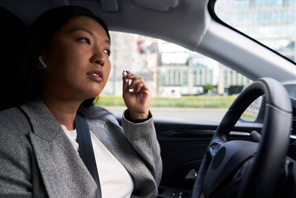 Chinese woman using earphones while driving a car - Valokuva, kuva