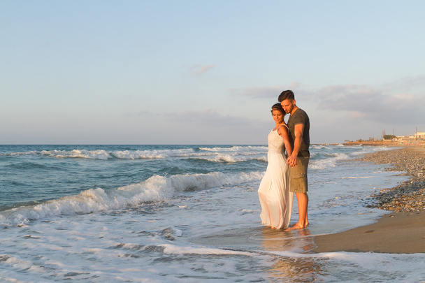 Giovane coppia gode di camminare su una spiaggia nebbiosa al tramonto
. - Foto, immagini