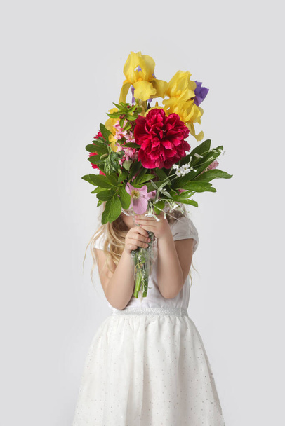 Studio portrait of beautiful little girl holding big colorful bouquet of various flowers. - Фото, зображення