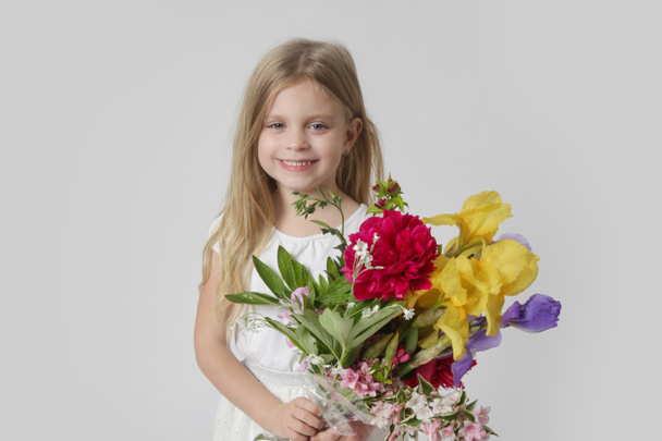 Studio portrait de belle petite fille tenant grand bouquet coloré de diverses fleurs. - Photo, image