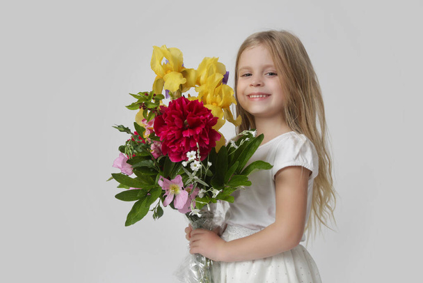 Studio portrait of beautiful little girl holding big colorful bouquet of various flowers. - Foto, imagen