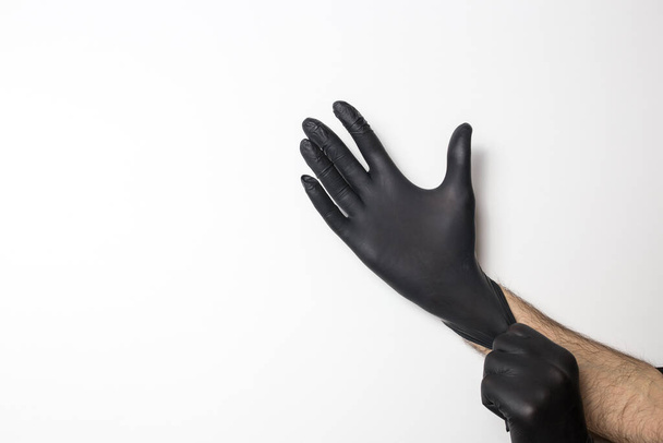 Medical black gloves on a male hand on a white background. - Valokuva, kuva
