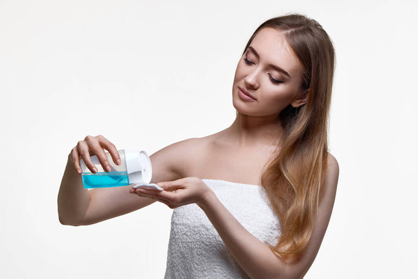 beautiful woman holding bottle with tonic, cleaning skin with cotton pad. Beauty and skin care concept - Фото, зображення
