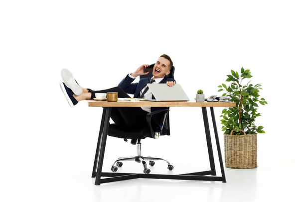 Successful happy businessman working with laptop and having phone conversation with client - Foto, immagini