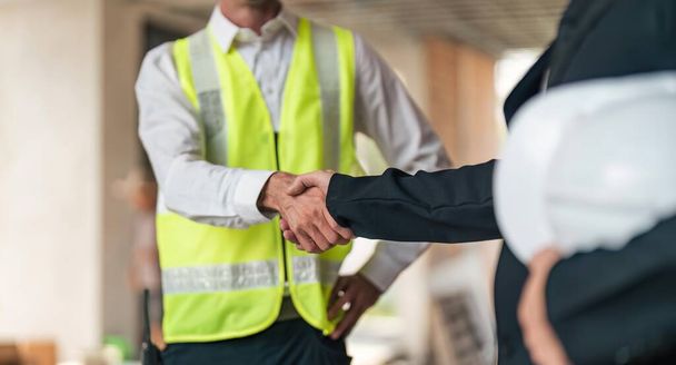 Happy young civil engineer manager and architects handshaking at construction site and looking to next construction phase , cooperation teamwork concept. - Foto, imagen