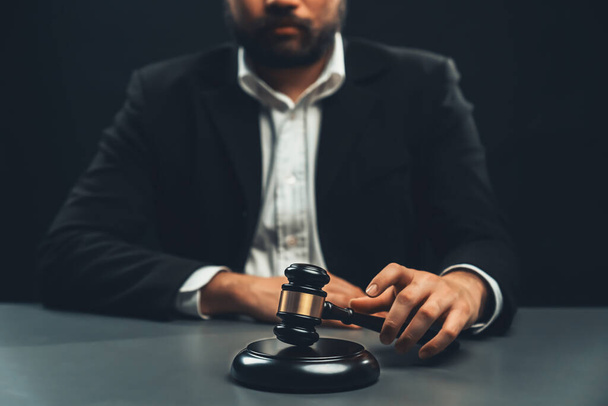 Fokus dřevěné kladivo kladivo s vroubkovaným zázemím právníka v černém obleku sedí na jeho kancelářském stole, symbol právní spravedlnosti a bezúhonnosti, vyvážené a etické rozhodnutí u soudu spravedlnosti - Fotografie, Obrázek