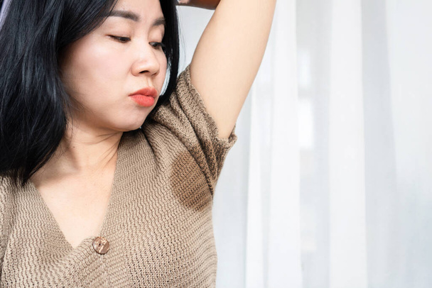 asiatico donna avendo problema con sudore puzzolente ascella mostrando il suo bagnato sotto braccio - Foto, immagini