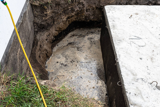 Concrete septic tank with a capacity of 10 cubic meters placed in the garden by the house, visible water below. - Photo, Image