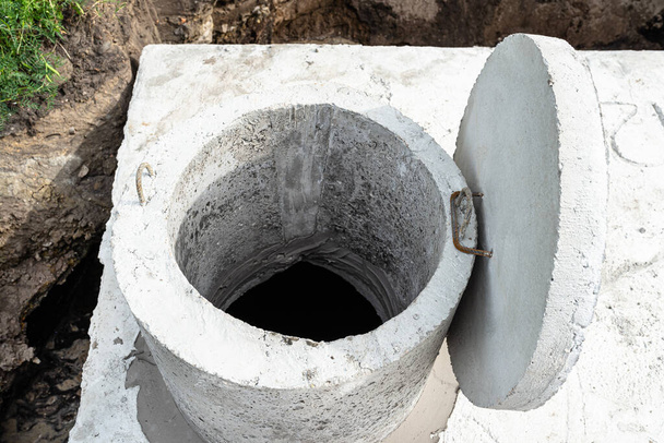 tanque séptico de concreto com uma capacidade de 10 metros cúbicos colocados no jardim pela casa, água visível abaixo. - Foto, Imagem