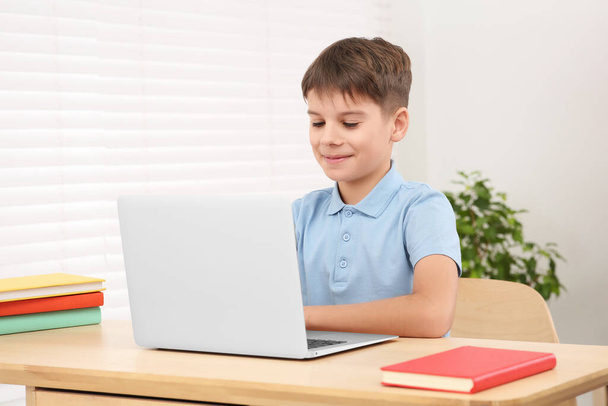 Boy using laptop at desk in room. Home workplace - Zdjęcie, obraz
