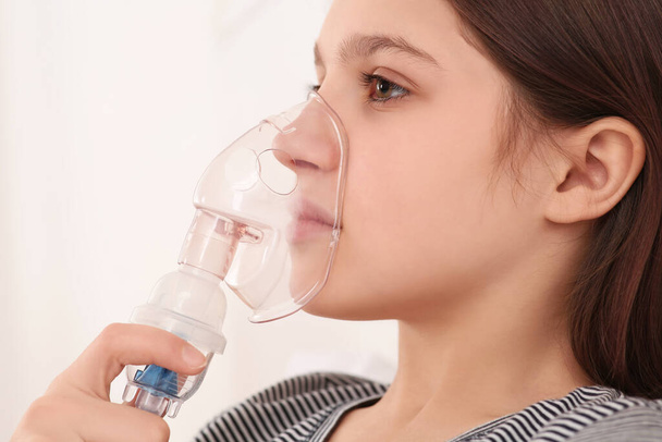 Cute girl using nebulizer for inhalation on white background, closeup - Фото, изображение