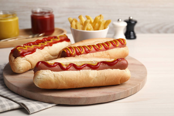 Fresh delicious hot dogs with sauces on white wooden table - Zdjęcie, obraz