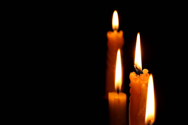 Burning candles on black background, closeup. Space for text - Valokuva, kuva