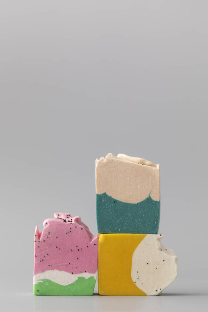 Pieces of different shapes and colors of handmade soap on a grey background. The concept of natural cosmetics, hygiene. Copy space - Fotoğraf, Görsel