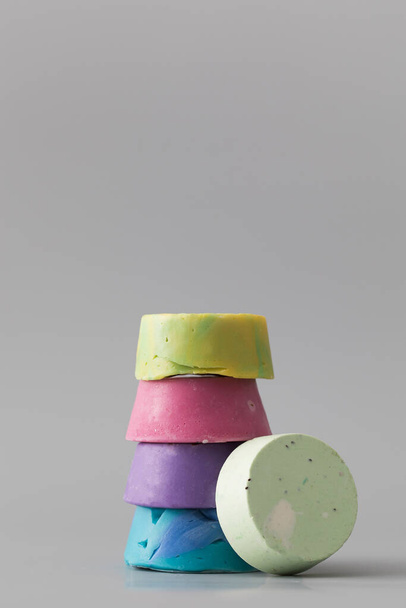 Stücke in verschiedenen Formen und Farben aus handgemachter Seife auf grauem Hintergrund. Das Konzept der Naturkosmetik, Hygiene. Kopierraum - Foto, Bild