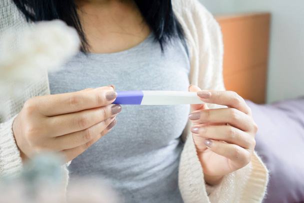 closeup woman hand holding pregnancy test looking at the positive, negative result, new life concept - Photo, Image