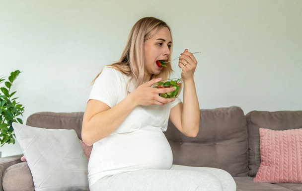 A pregnant woman eats a salad with vegetables. Selective focus. Food. - Foto, imagen