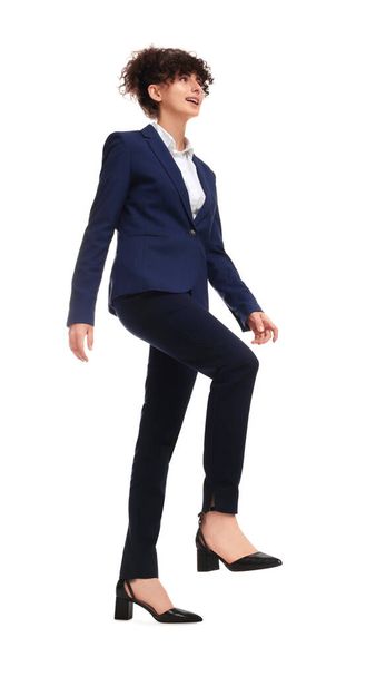 Beautiful businesswoman in suit walking on white background, low angle view - Fotó, kép