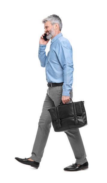 Mature businessman talking on smartphone against white background - Фото, изображение
