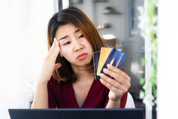 surullinen aasialainen nainen, jolla on ongelmia velan kanssa, yli rahaa ostokset käsi tilalla luottokortti ja huolehtia myöhässä, määräaika maksu - Valokuva, kuva