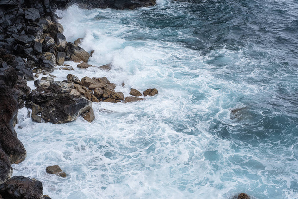 Skały klifu. Fale uderzające o skały wulkaniczne klifu. Ciężki ocean. Czarne skały. Puerto de la Cruz, Teneryfa, Wyspy Kanaryjskie, Hiszpania. - Zdjęcie, obraz