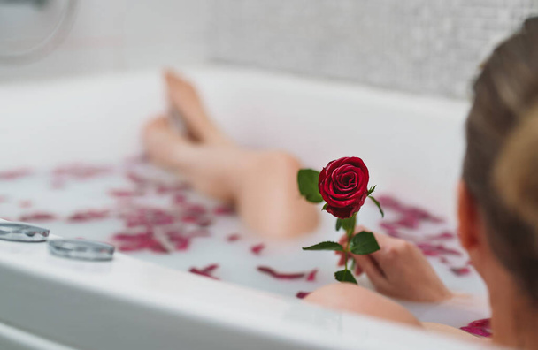 Жінка відпочиває в ванні з молоком і пелюстками троянд
. - Фото, зображення