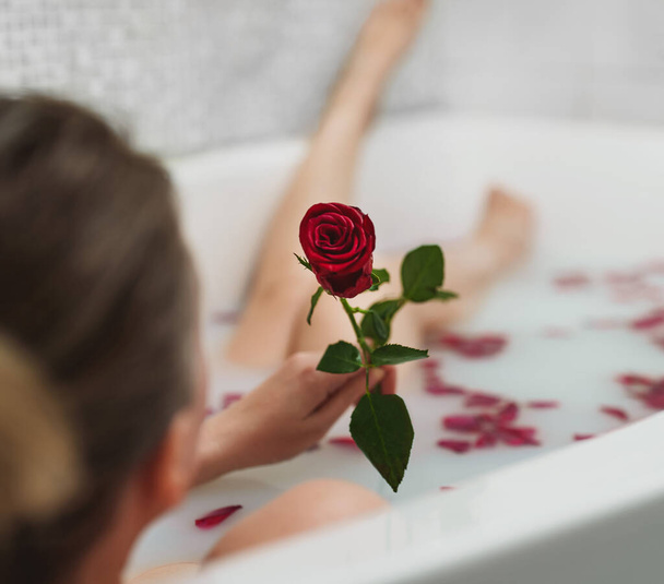 Femme se détend dans un bain avec du lait et des pétales de rose. - Photo, image