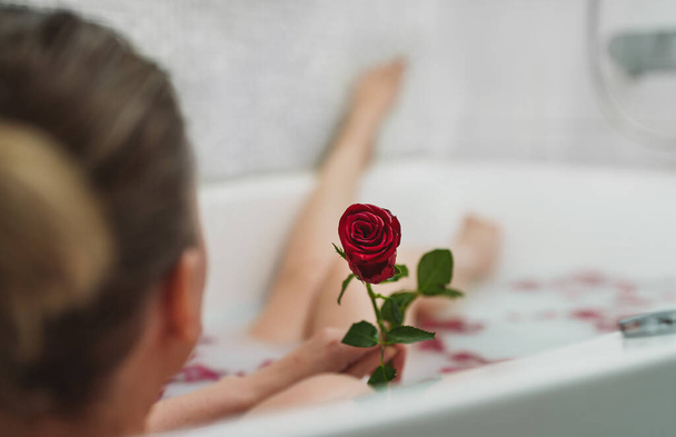 Woman relaxes in a bath with milk and rose petals. - Valokuva, kuva
