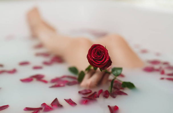 Woman relaxes in a bath with milk and rose petals. - Foto, Bild