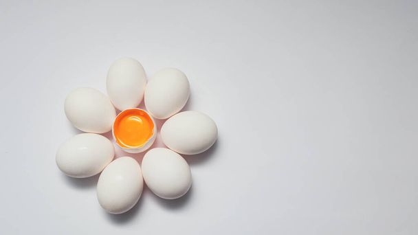 Uovo crudo a forma di fiore. Uova bianche, intere e spezzate metà uovo con un tuorlo isolato su fondo bianco - Foto, immagini