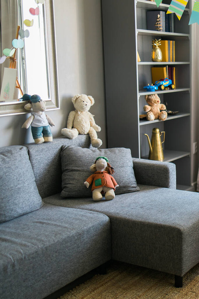 Stylish scandinavian nursery interior with shelves teddy bear and toys. Hanging flags cozy and sunny child room concept - Foto, immagini