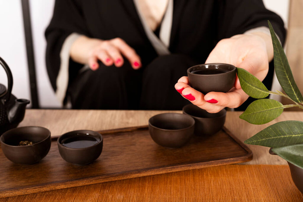 Attractive white girl in kimono and Hair sticks drinks tea in japanese style. Japanese tea ceremony. - Foto, afbeelding