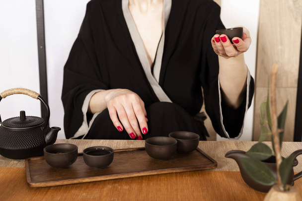 Привлекательная белая девушка в кимоно и палочках для волос пьет чай в японском стиле. Японский чай. - Фото, изображение
