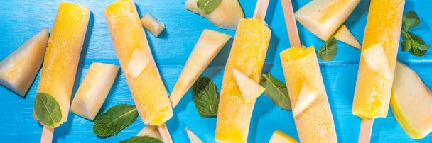  Melon ice cream popsicle, sweet sorbet lollypops, homemade gelato on sticks, with slices of fresh cantalupa melon and mint leaves  - Photo, image