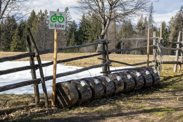 Oryginalna stacja ładowania rowerów elektrycznych zbudowana z drewnianych kłód do parkowania rowerów - Zdjęcie, obraz