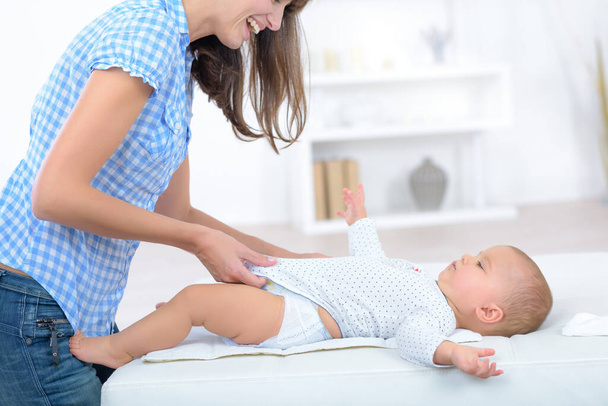 mother dressing baby after changing nappy - Foto, Bild