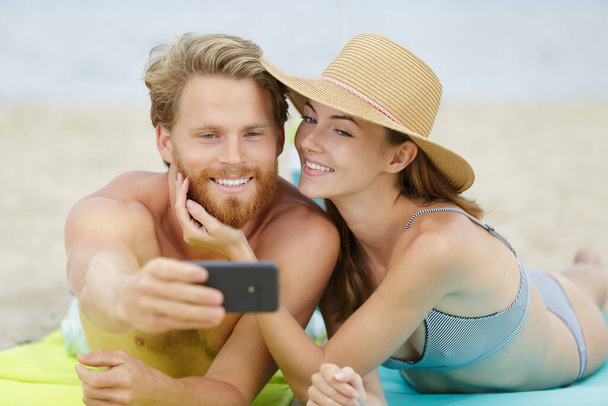 fit couple taking selfie with smart phone on the beach - Foto, Imagem