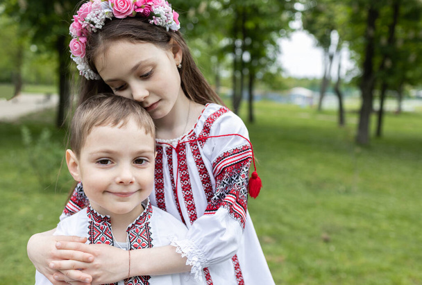 Ragazzo di 4 anni, ragazza di 7 anni in abiti nazionali ucraini ricamati sedersi abbracciando. Il giorno dell'indipendenza dell'Ucraina. I bambini dovrebbero vivere in pace e tranquillità. Sostenere, aiutare l'Ucraina. Cura, famiglia - Foto, immagini
