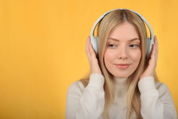 χαριτωμένο νεαρή ξανθιά γυναίκα απολαμβάνοντας τη μουσική στα ακουστικά - Φωτογραφία, εικόνα