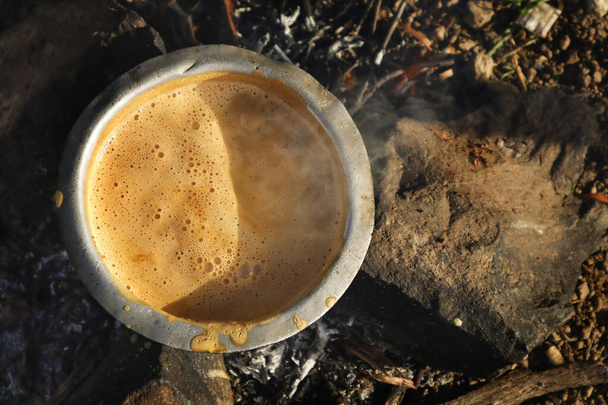 im Wald ein Feuer zum Kochen bringen. Teezubereitung auf traditionelle Art und Weise Chai auf offenem Feuer in der alten indischen Küche. Töpfe und Pfannen auf dem Herd über einem natürlichen Feuer mit Bio-Holzbrennstoff zum Kochen - Foto, Bild