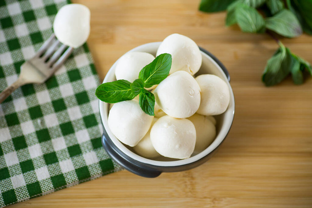 Small balls of traditional mozzarella in a ceramic bowl with mint - Фото, зображення
